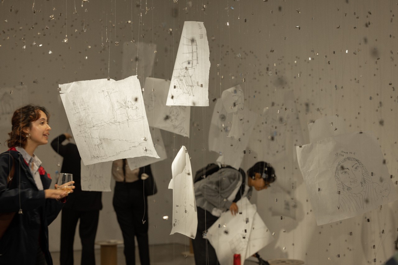 A student walking in the middle of a paper installation at an art gallery