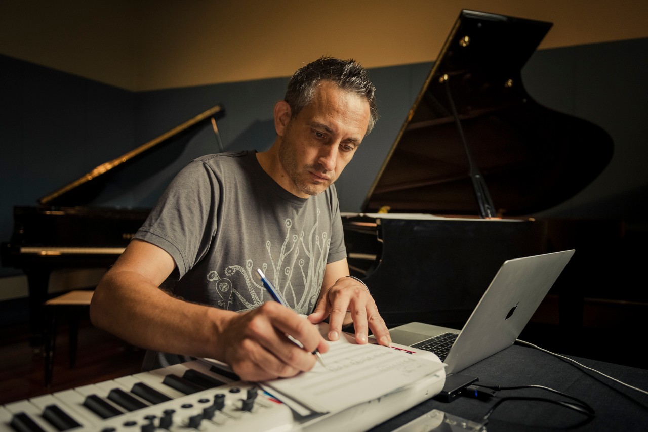 photo of a map sitting at a piano with a laptop open 