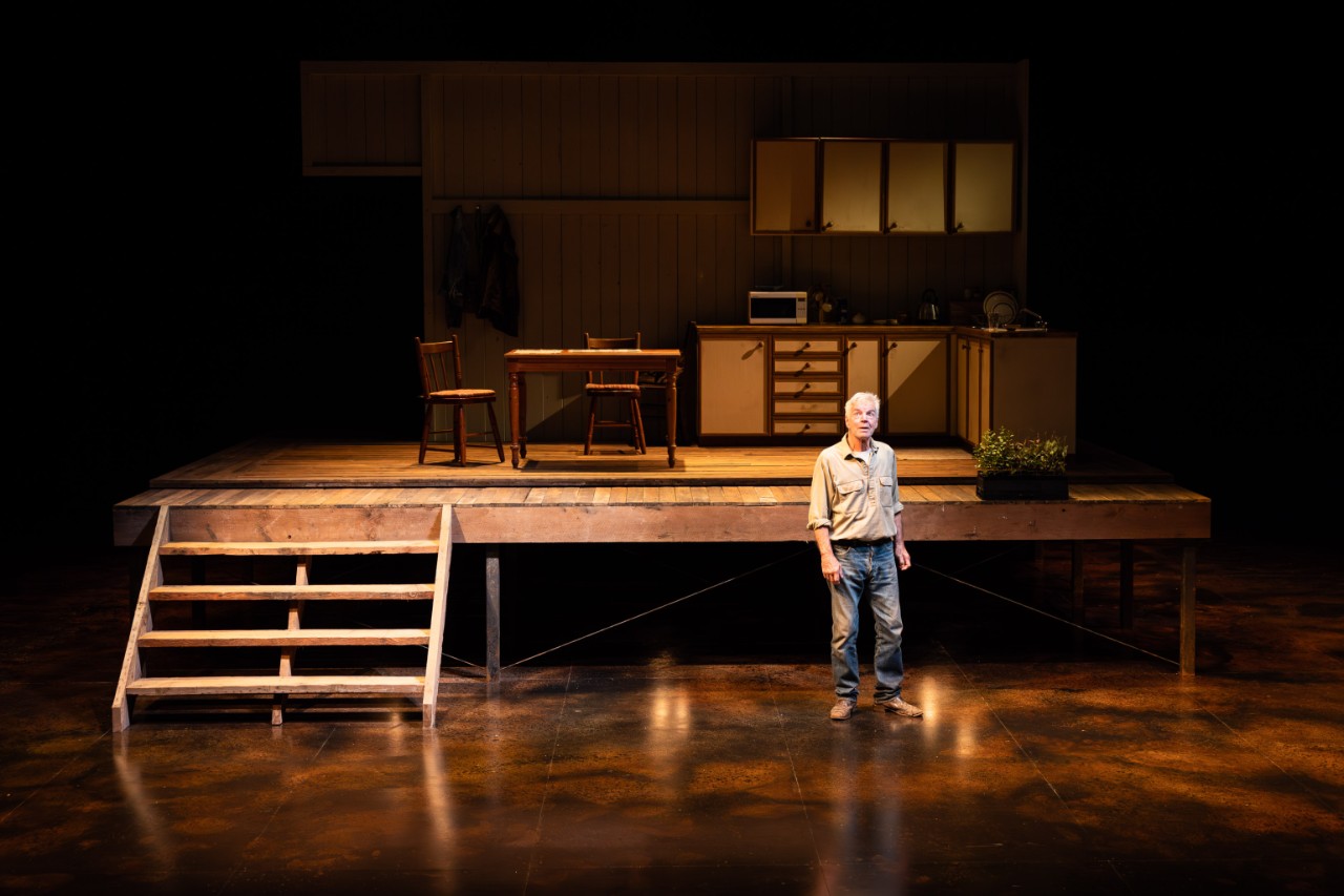 a male actor stands in front of a set of a house