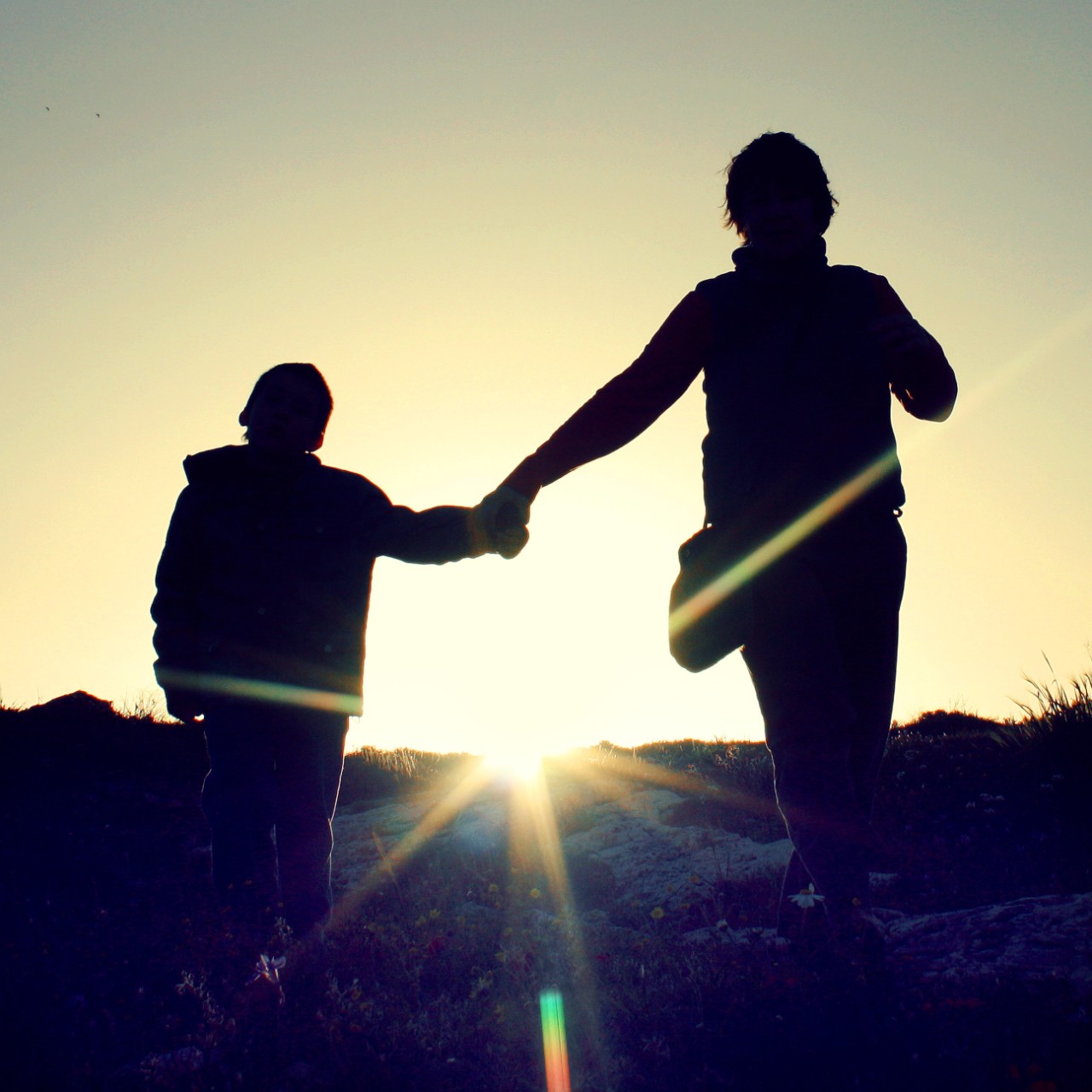 A photo of a mother and child walking in silhouette.