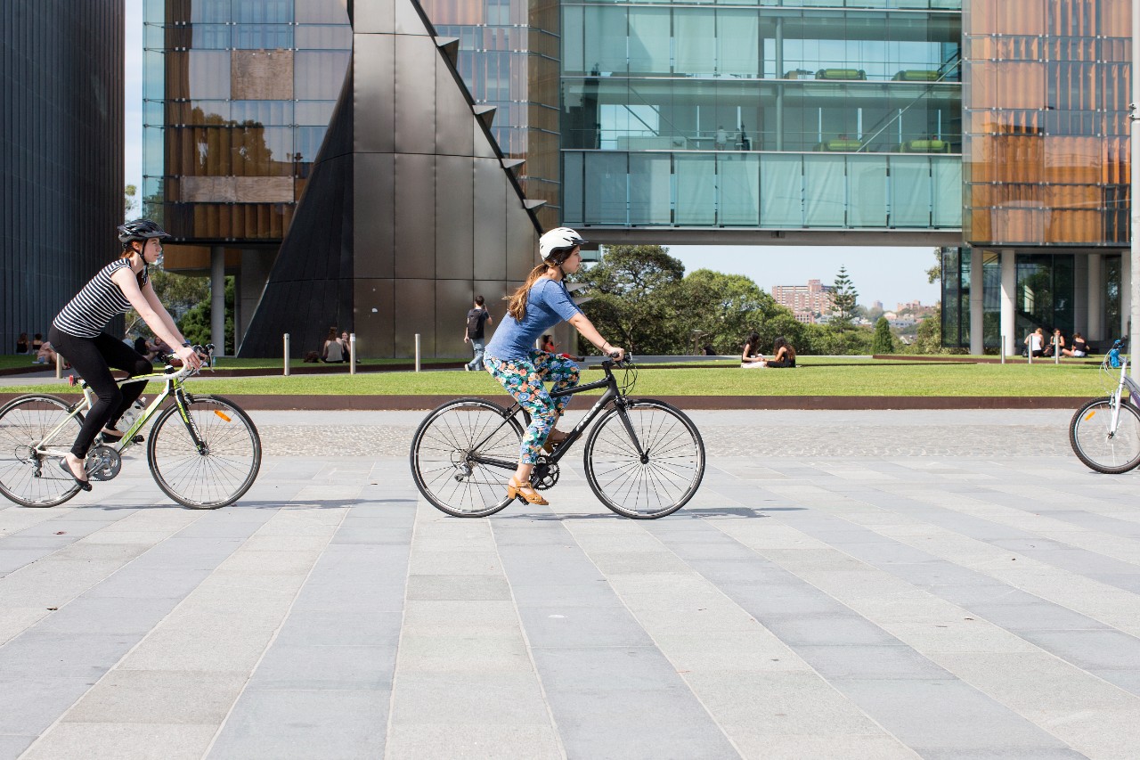 Students riding bikes down Eastern Avenue in front of the New Law Annex Building.