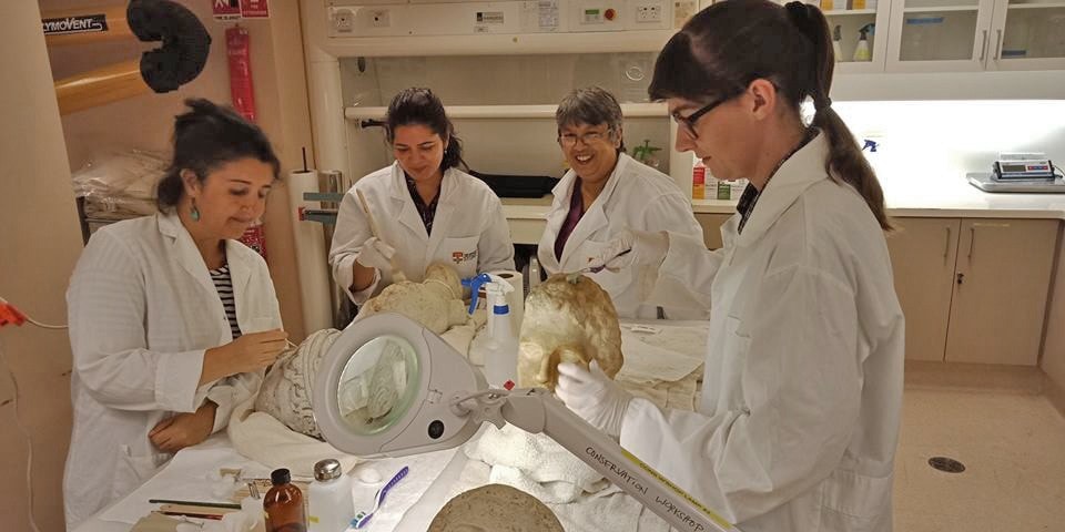 Team of conservators in white lab coats with artefacts.