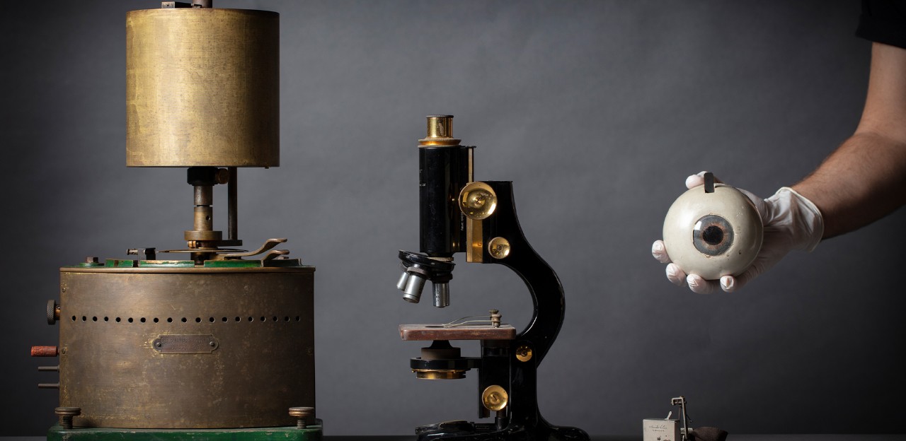 Brass physiology objects, one being held by a gloved hand.