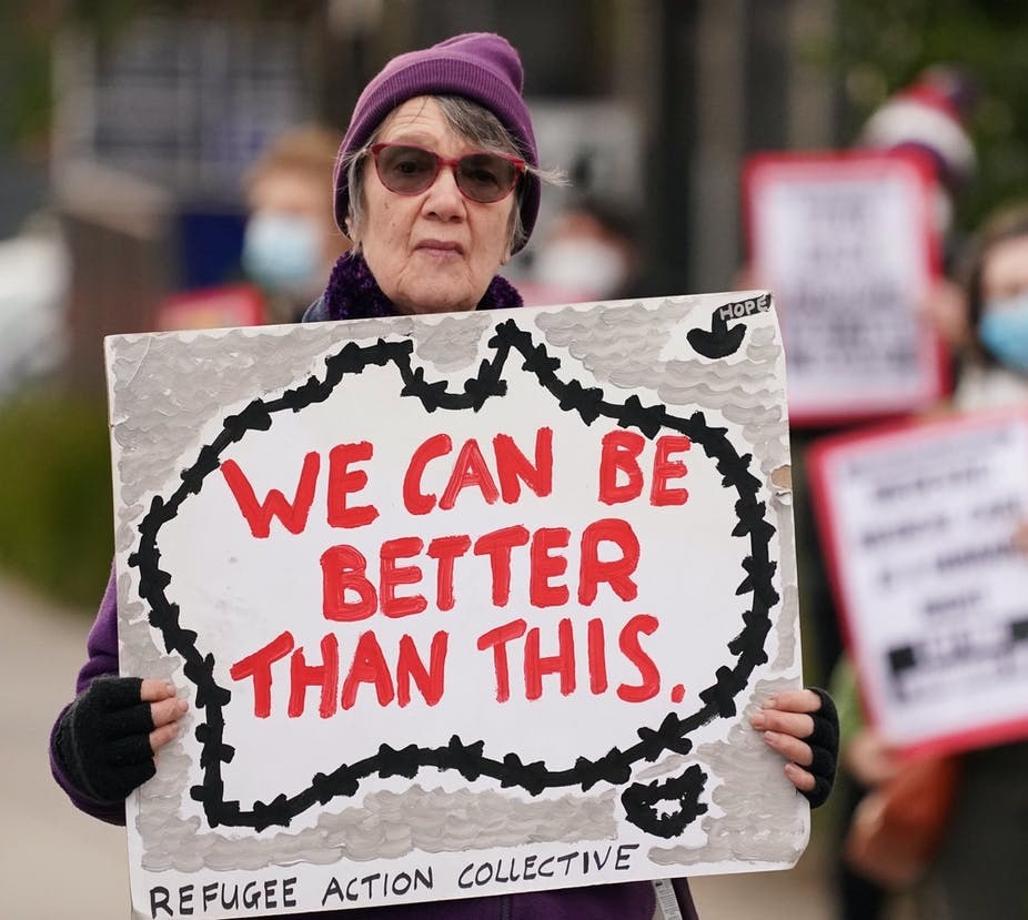 Woman holding a sign that reads 'we can be better than this'
