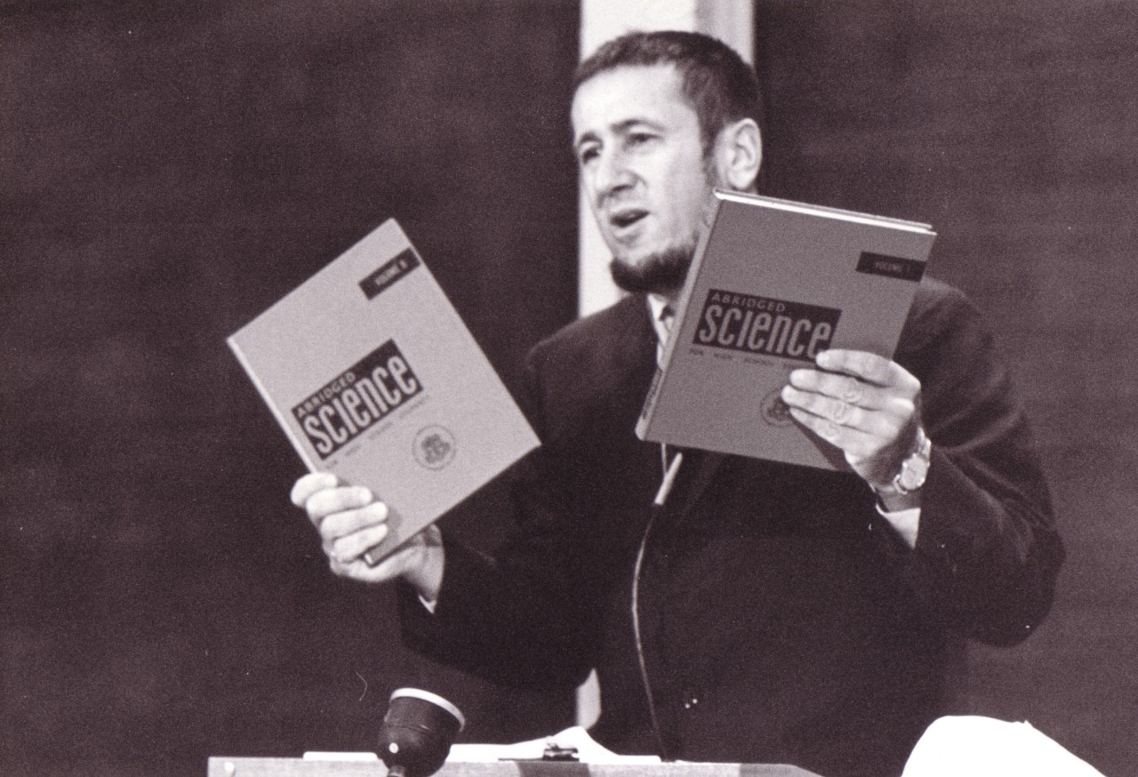 Harry Messel holding up two science textbooks in the classroom