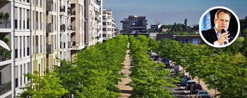 Image of a road lined with trees and apartments on the left side