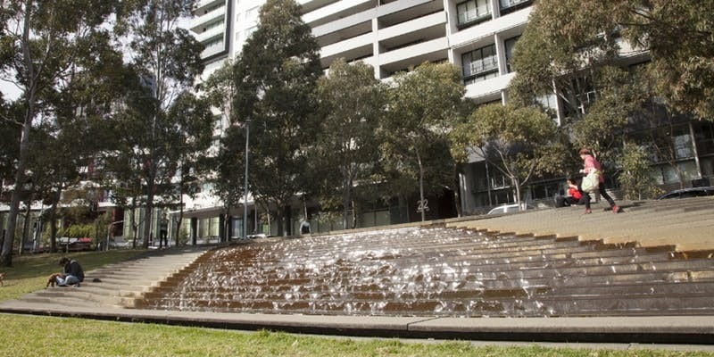 Park with a water fountain and people sitting on steps