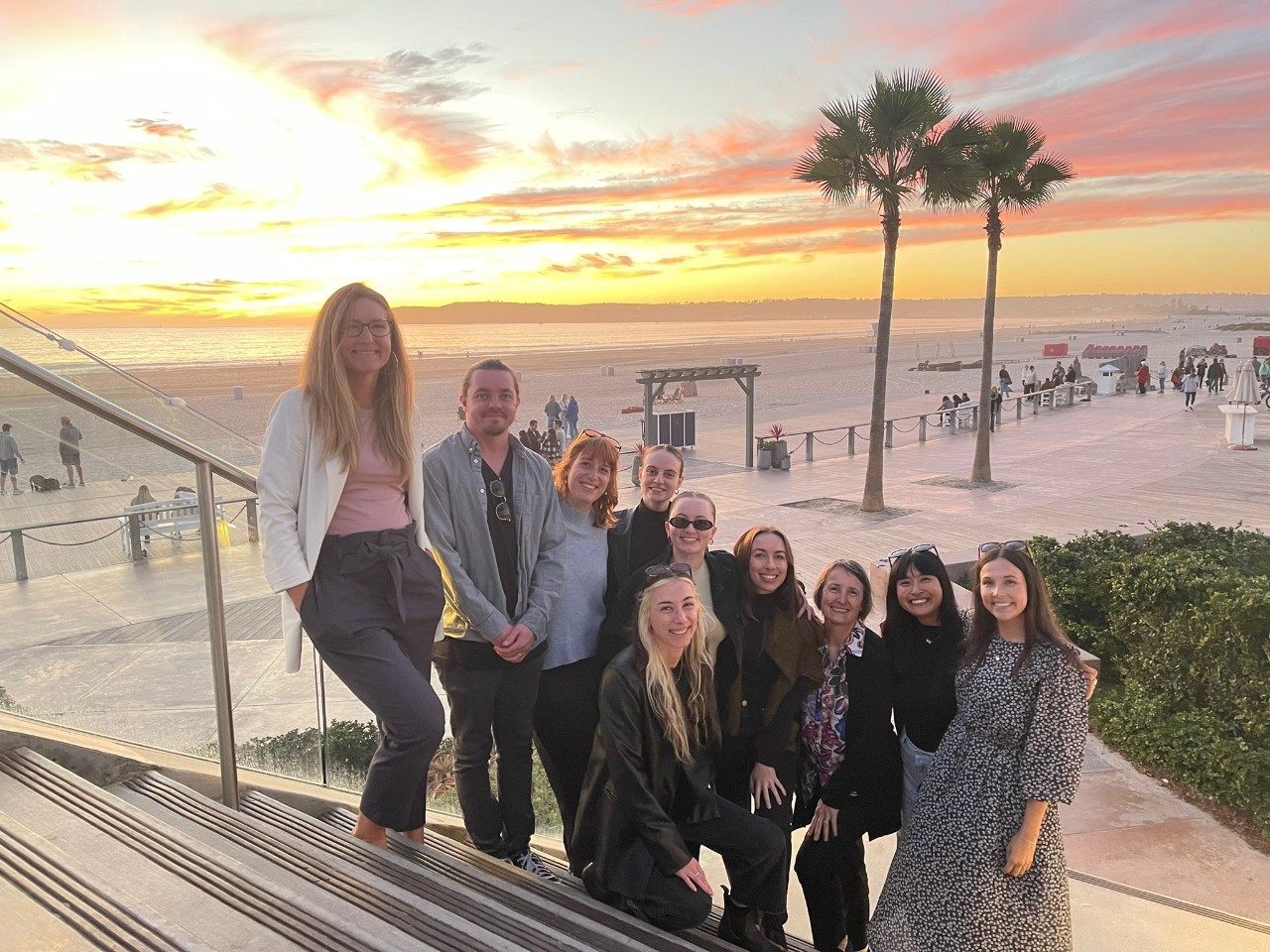 A group of people standing in front of the sunset. 