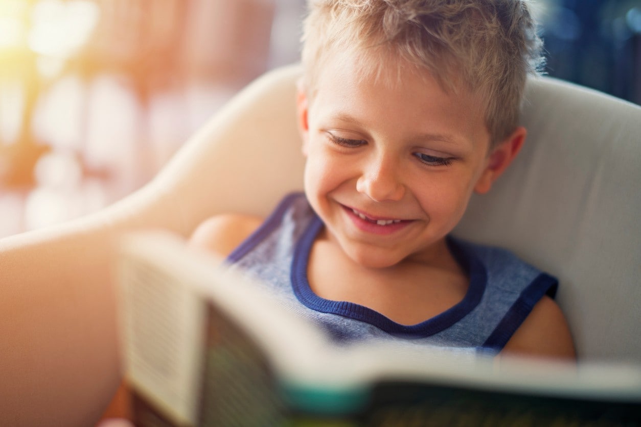 A young child happily reads a book. Image: iStock