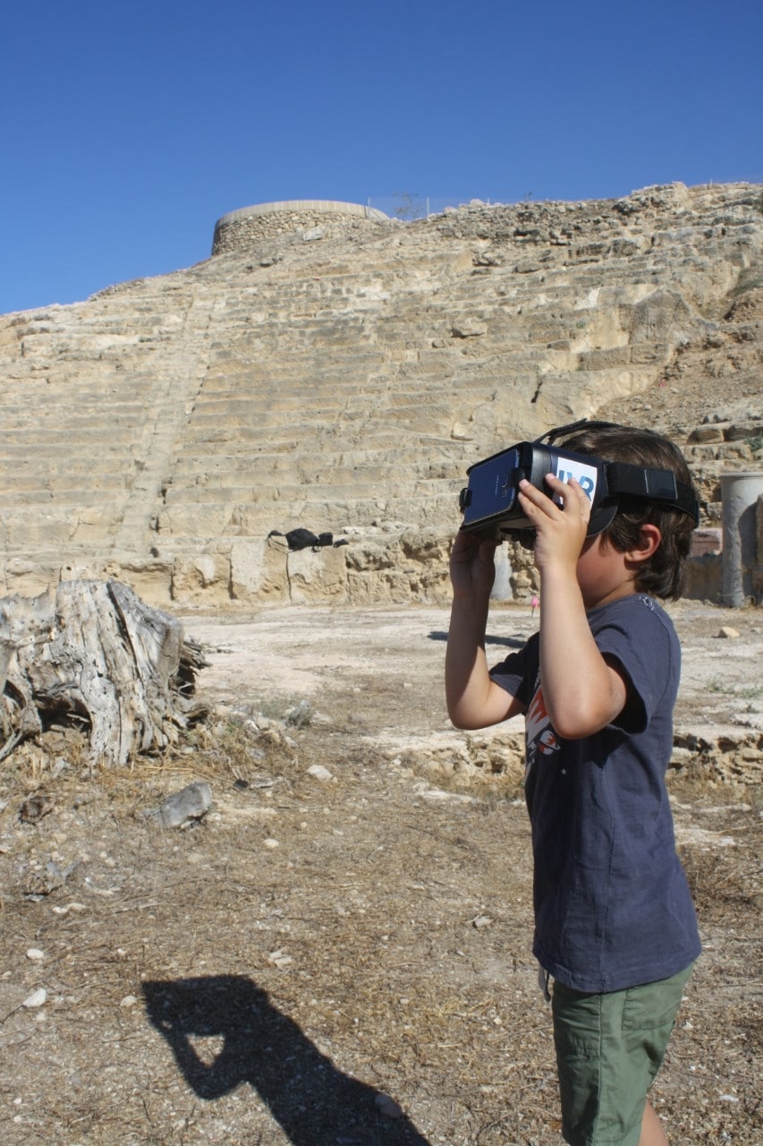 A school child on site at Nea Paphos looking at the virtual reality mobile application depicting the Nea Paphos Theatre in its heyday