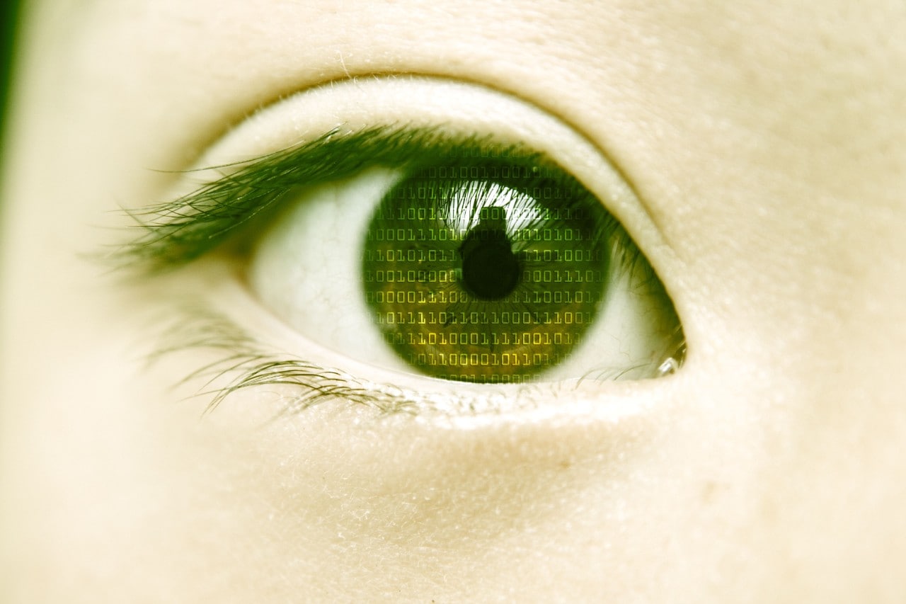 Closeup of woman's eye with binary code reflected in pupil.