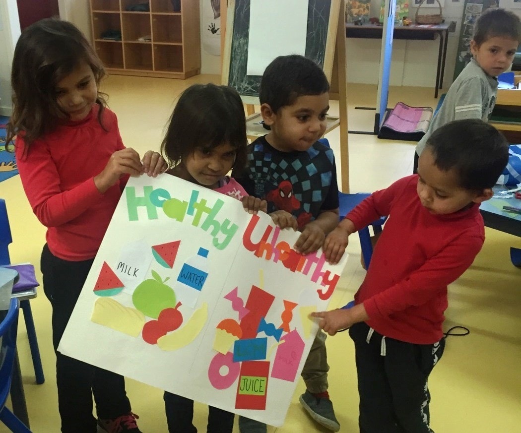 Young Aboriginal students holding up an artwork showing healthy and unhealthy foods