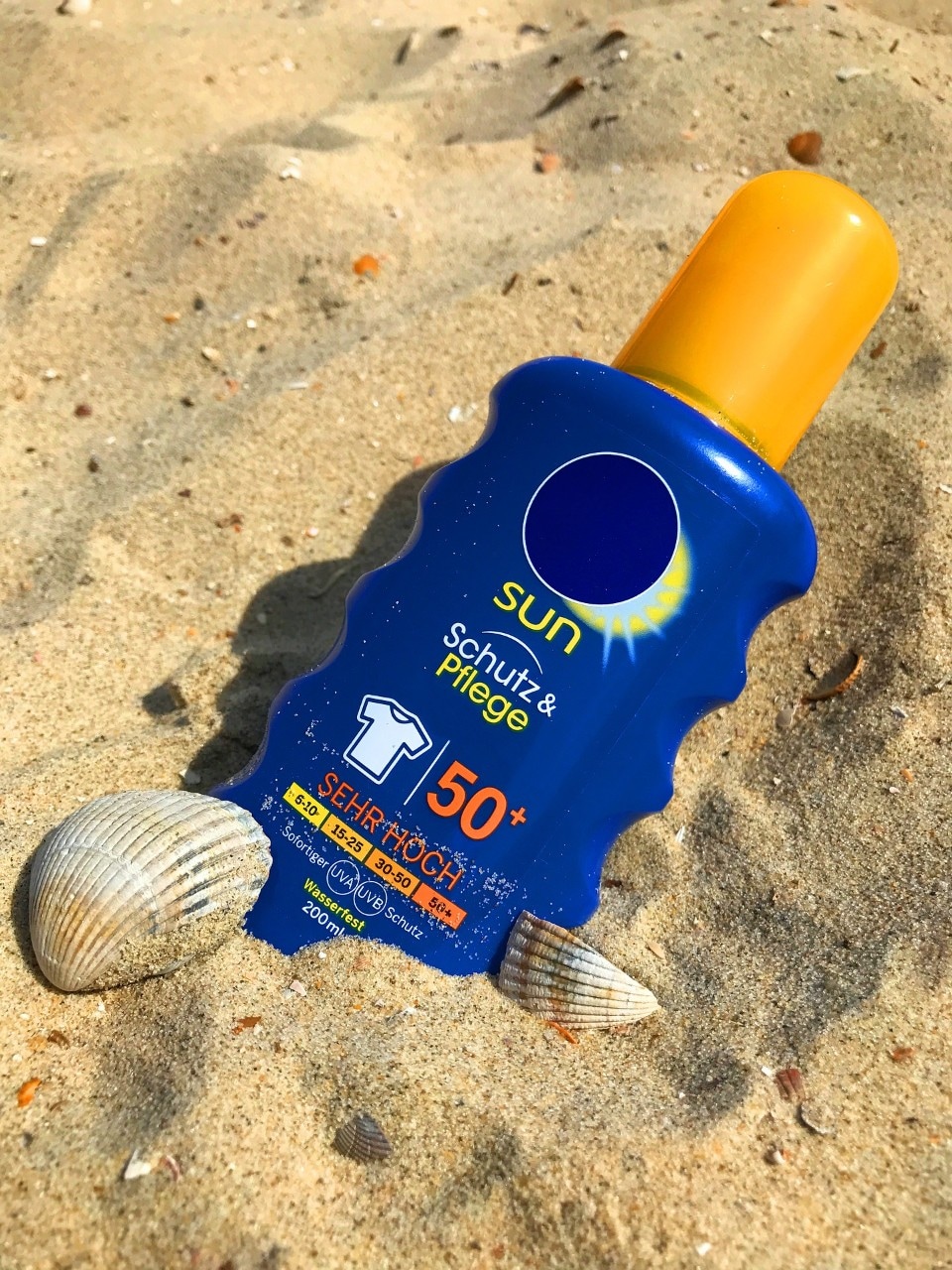 Sunblock in the sand with 'SPF 15' and 'UVA and UVB protection' on the label.