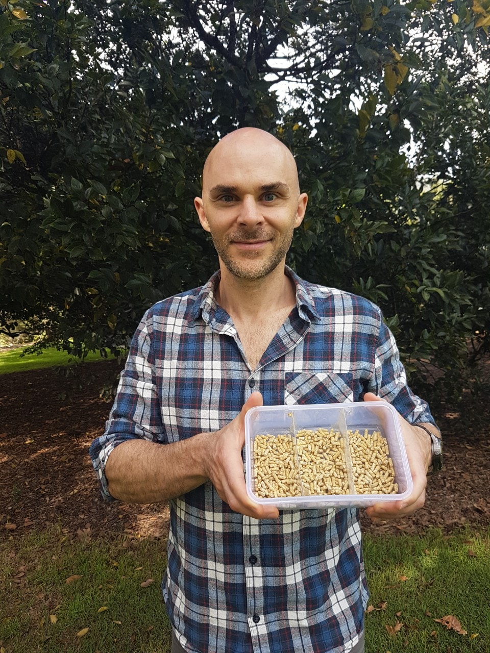 A photo of researcher Sean Coogan in Hyde Park Sydney, with container of ibis feed.
