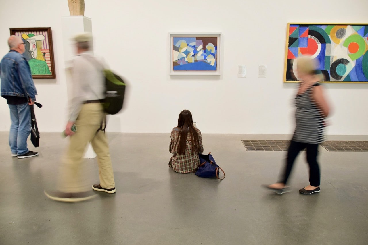 photo of people looking at abstract paintings in an art gallery