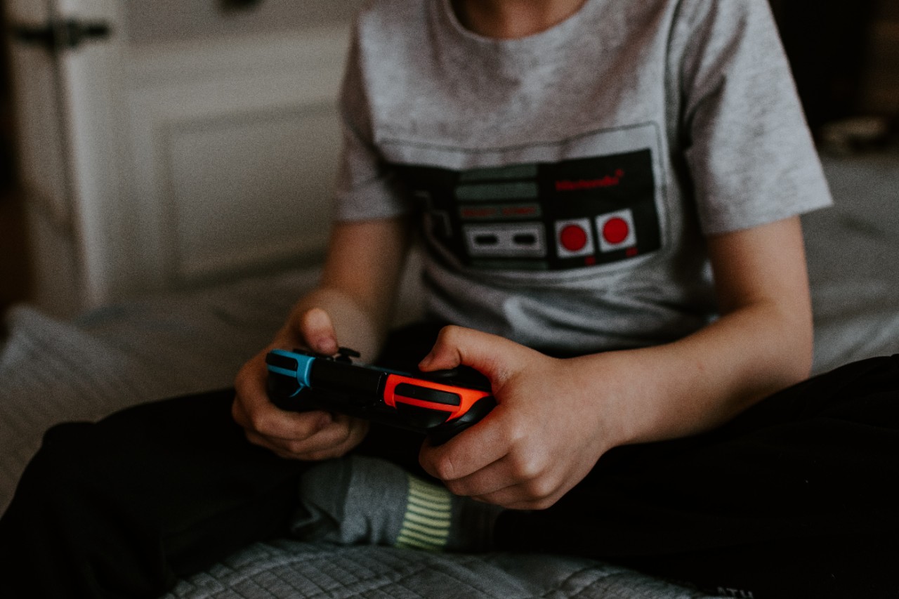 Photo of a boy on a bed with a gaming controller in his hands