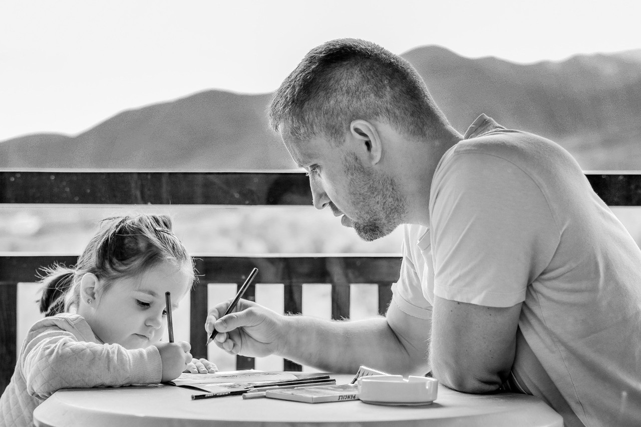 Photo of a father helping his daughter with her school work 