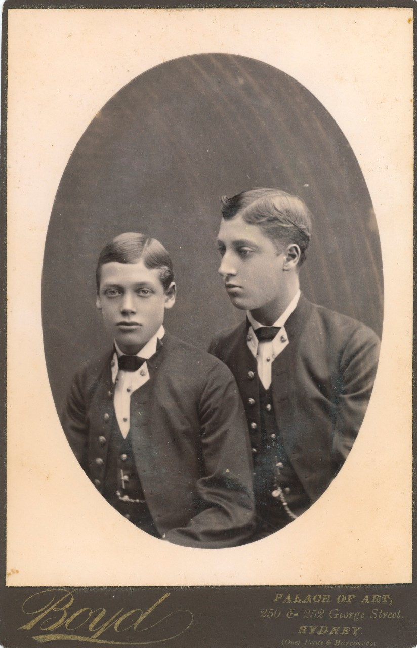 Black and white oval shaped image of Georg and Albert Victor, the royal princes, taken in a studio. Both are wearing suits. 