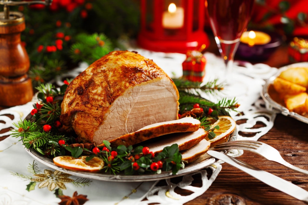 Roasted ham on a Christmas themed table 