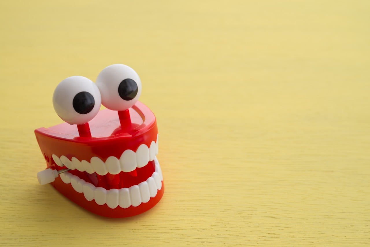 A toy set of teeth with eyes against a yellow background.