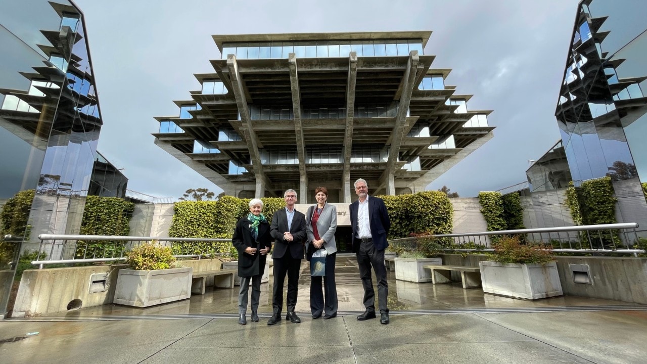 University of Sydney delegation stand in front of an architechturally striking library building with concrete and glass