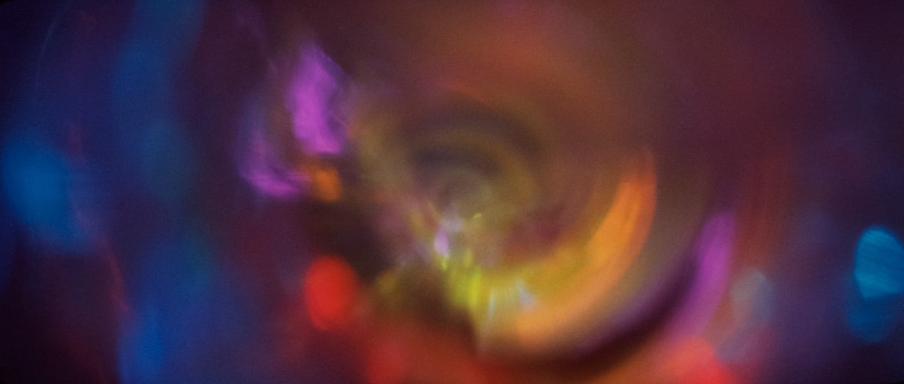 a film image of simple swirling colours in blue, yellow and pink
