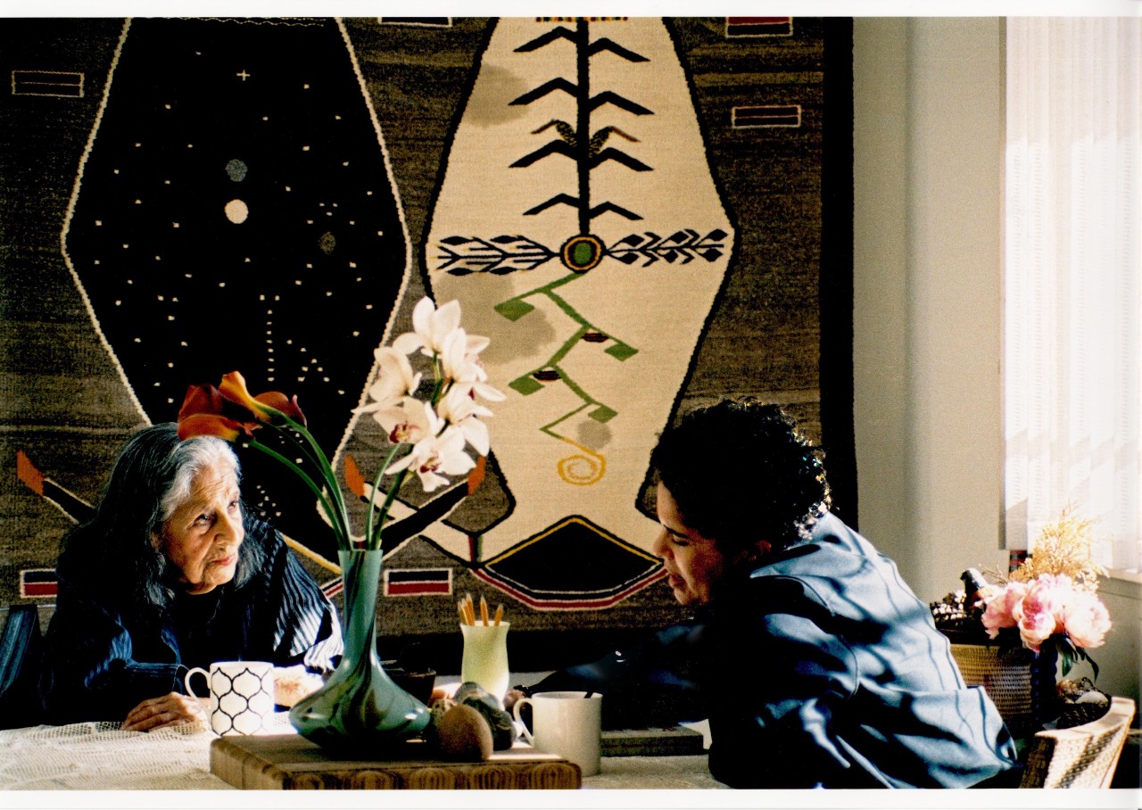 Two older women at a table drinking tea and talking, they are artists Julie Mehretu in conversation with the 99-year-old Venezuelan-born artist Luchita Hurtado 