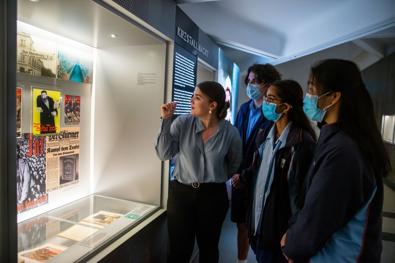 Students stand by glass case filled with artefacts in the Sydney Jewish Museum