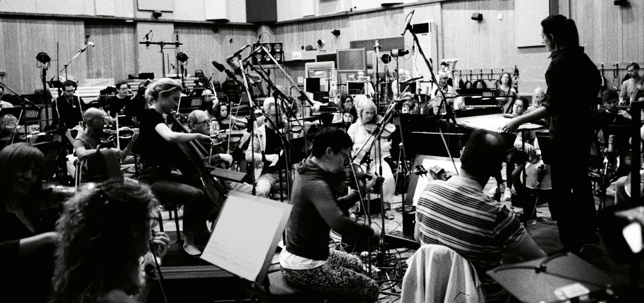 a black and white photo of an orchestra packed tightly in chairs in the small Abbey Road Studios with Natalie Murray Beale