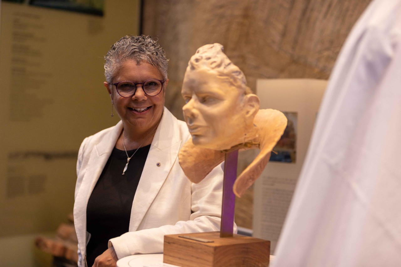photo of Deborah Cheetham Fraillon,an older indigenous woman with short curly hair, looking at the bust 