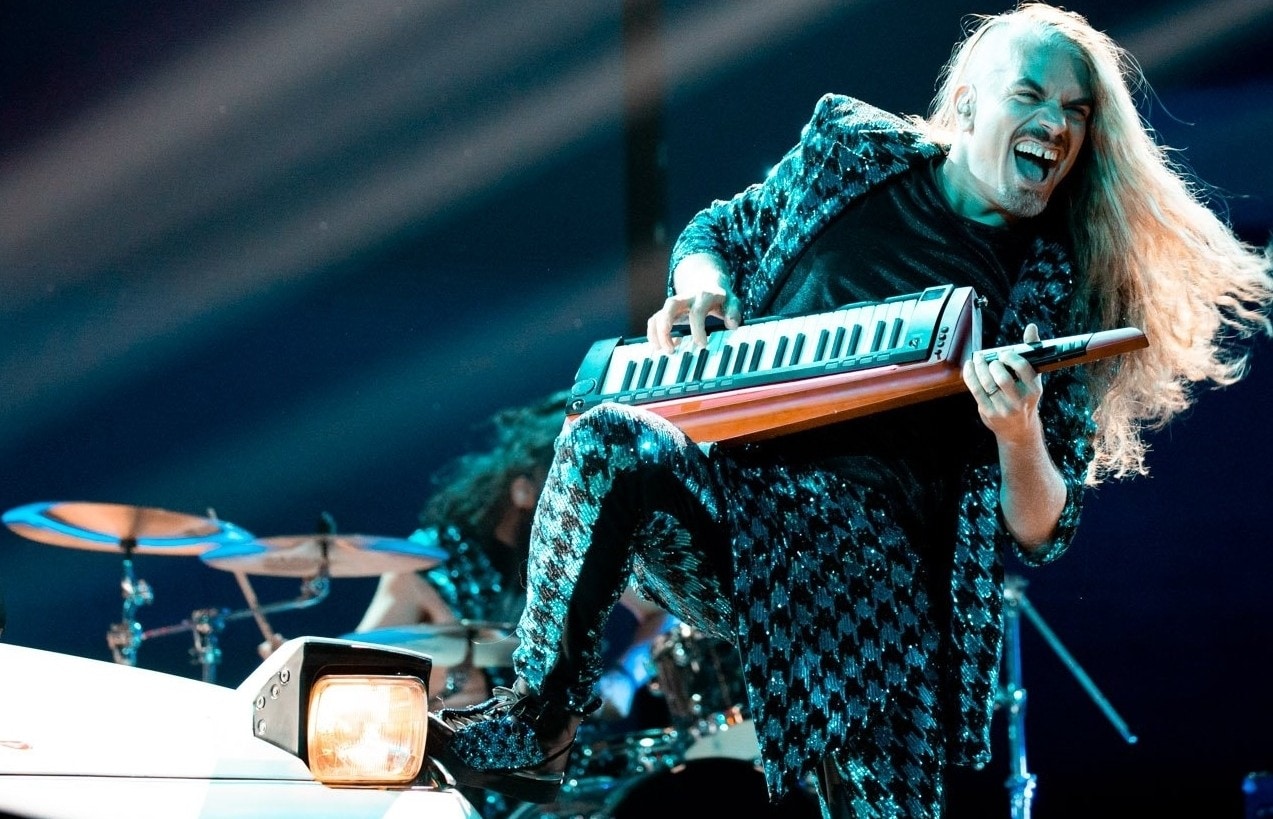 photo of a man with long blonde hair playing a keytar
