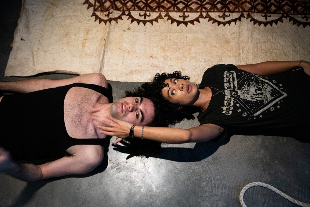 two students lying on the ground in a dance performance