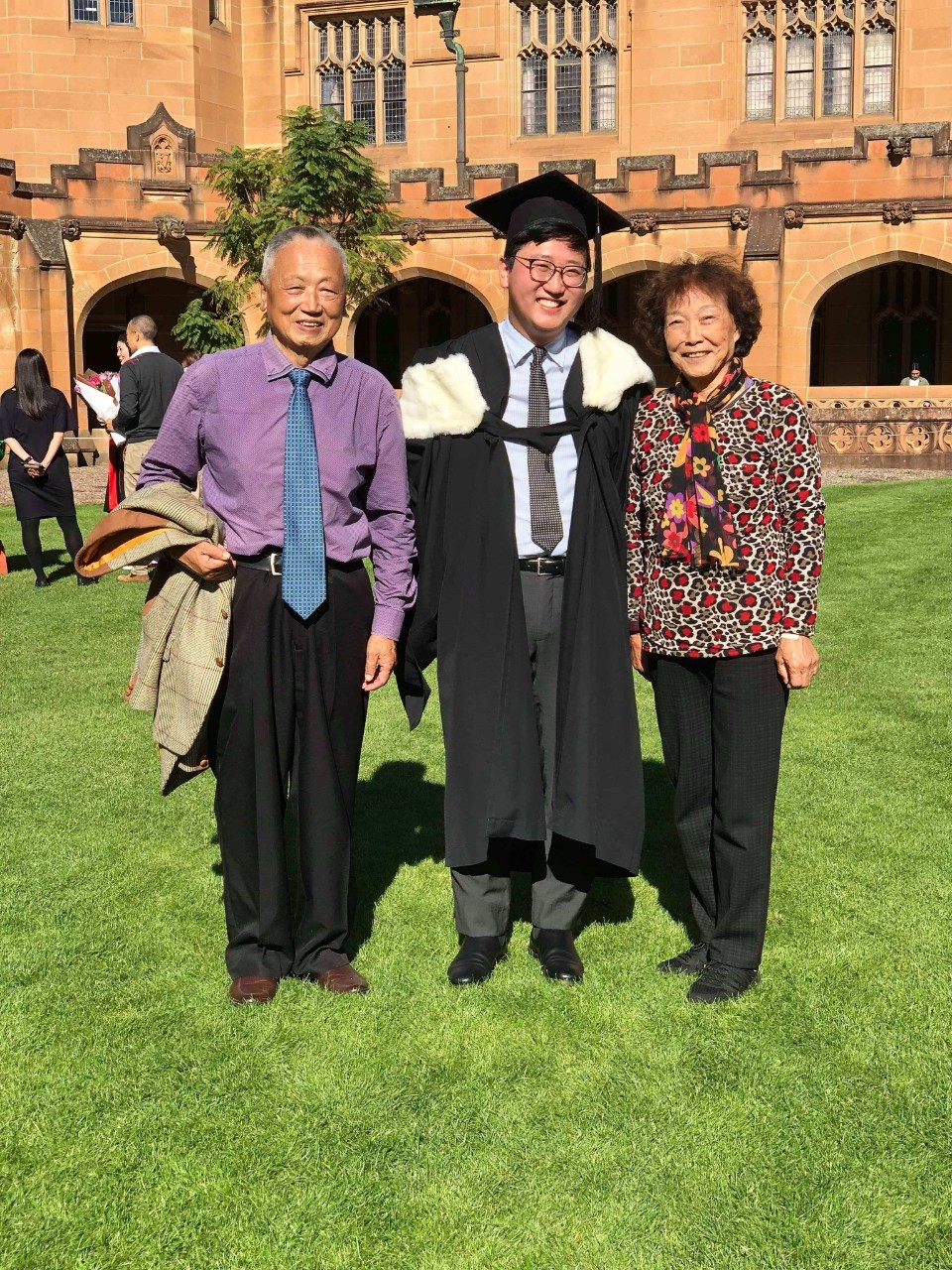 Alan Zheng in graduation regalia with grandparents. 