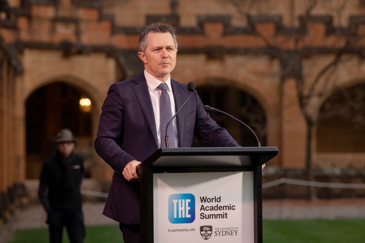 Jason Clare speaking at a lectern stand in the Quadrangle