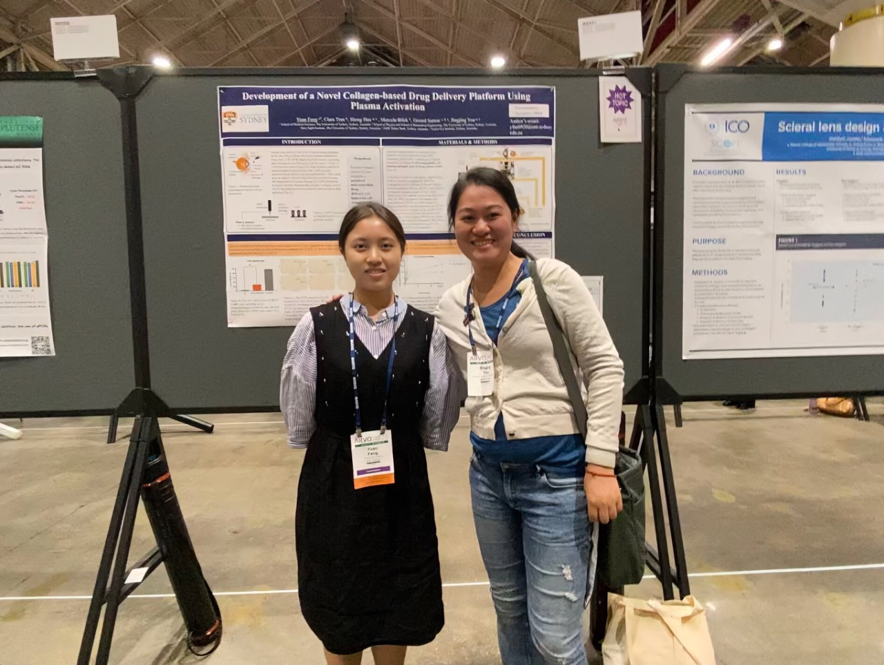 Photo of Yuan Fang and Jingjing You posing in front of a poster at a conference