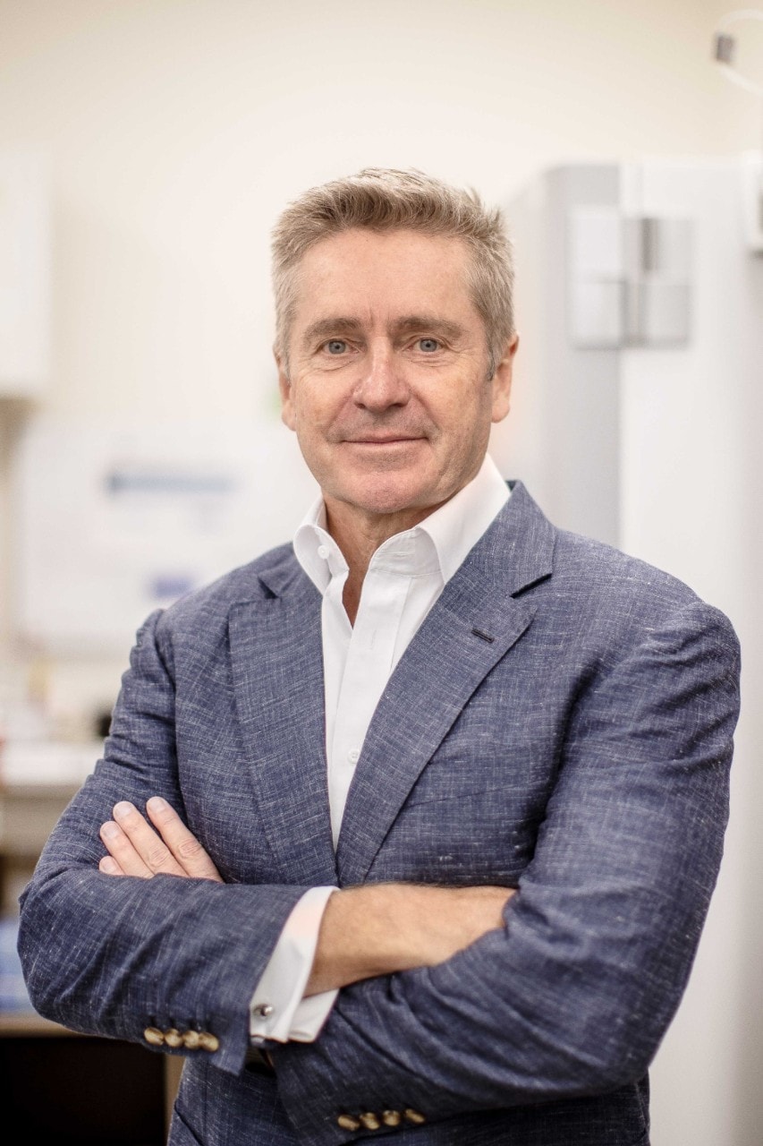 Portrait photo of Professor Gerard Sutton in a lab at the Save Sight Institute, wearing a grey suit jacket with arms crossed.