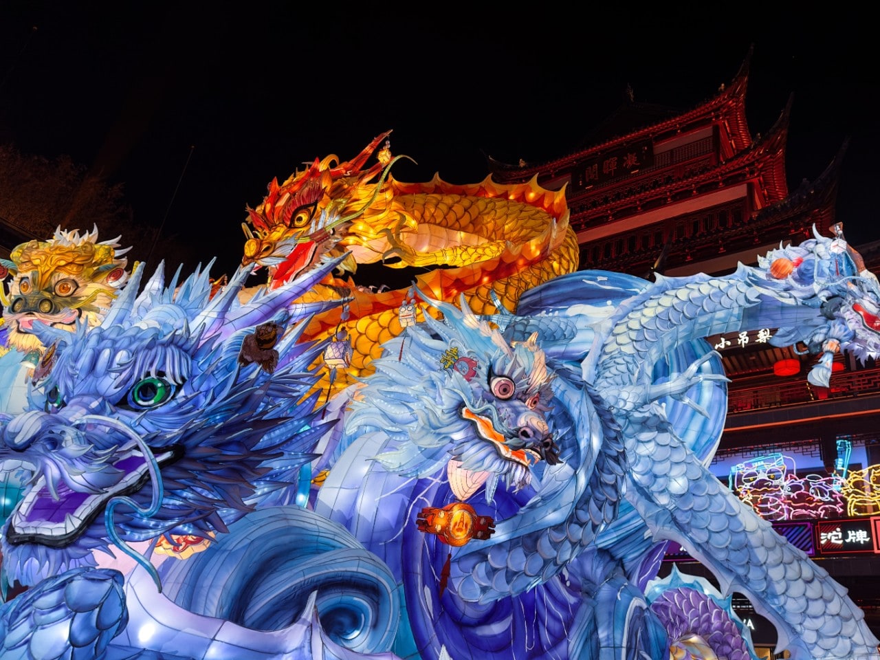 Bright blue lanterns in the shape of dragons in the street at night time