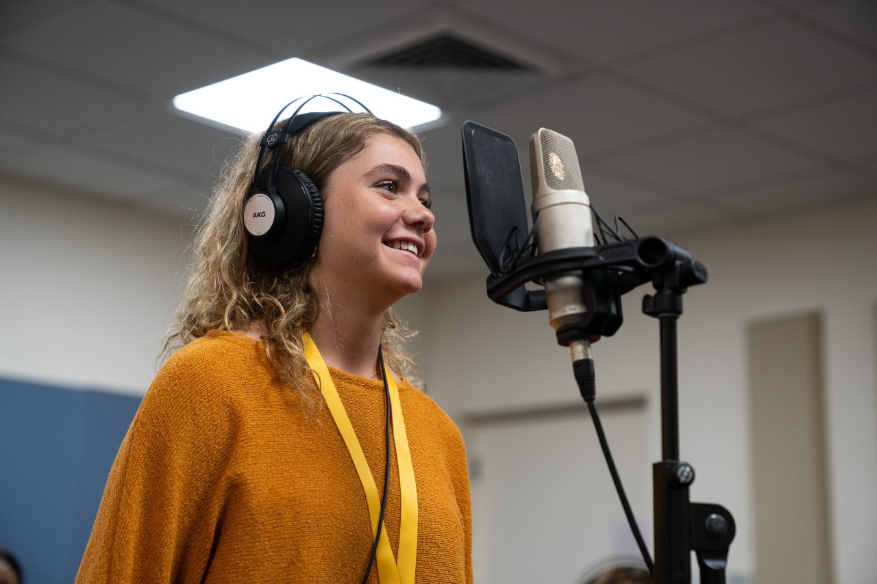 Aurielle Smith singing into a microphone in a recording student