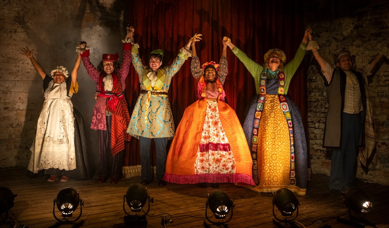 a group of actors bowing to the audience, they are wearing brightly coloured costumes