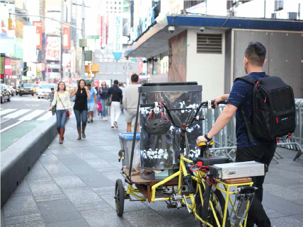 Steven Bai wheeling a bike in a city