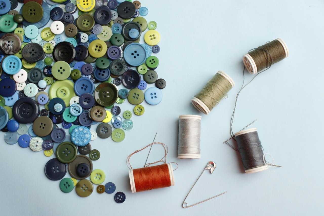 An array of buttons and thread against a blue background.