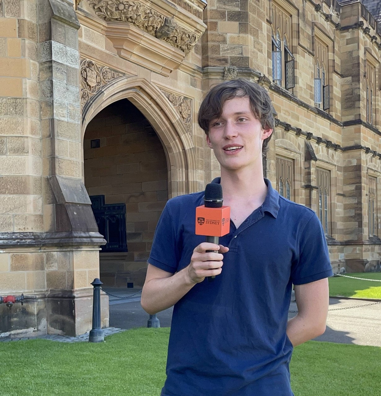 First year student Oscar standing at the front of the Main Quadrangle with a microphone