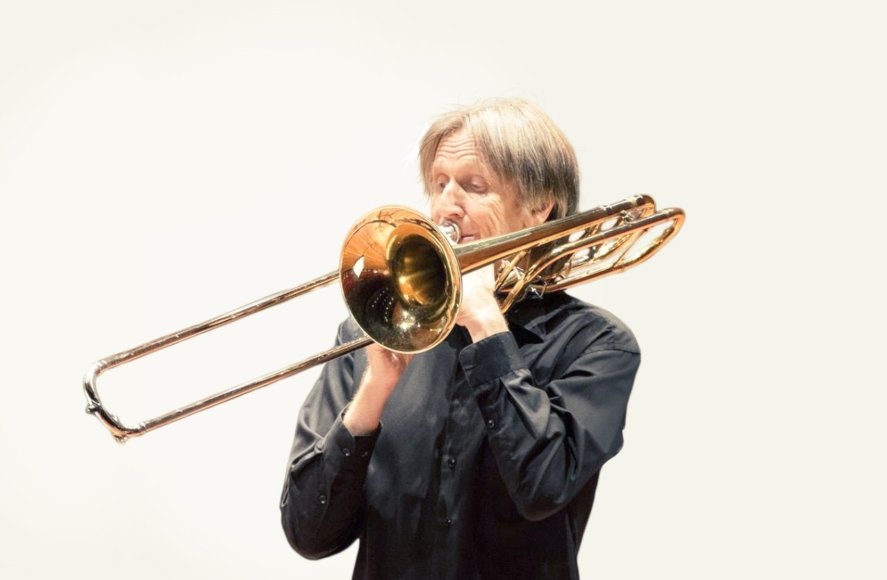 photo of man smiling at the camera with a trombone