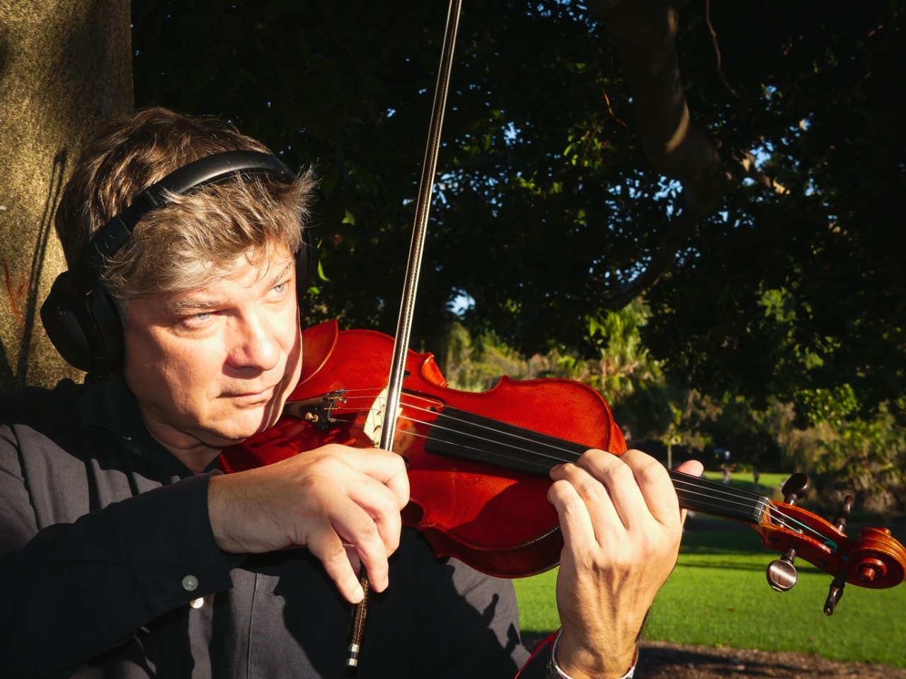 man playing a violin with headphones on