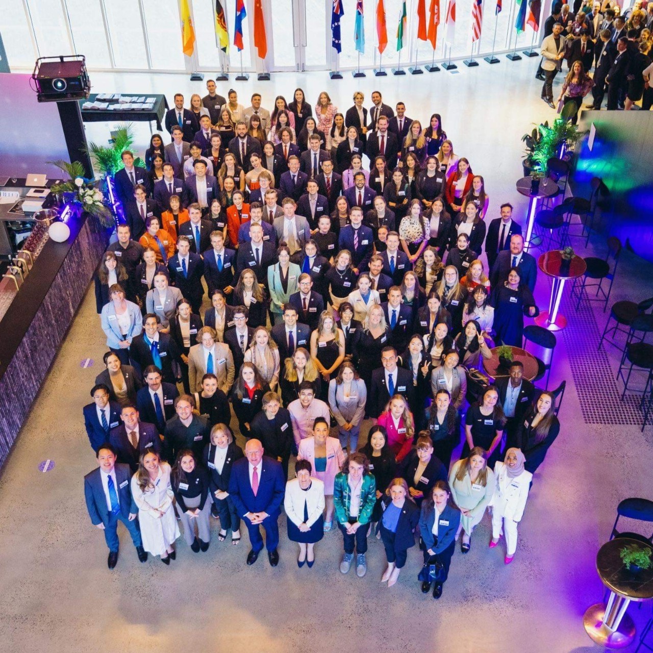 Group of scholarship students with flags from diffferent countries behind them