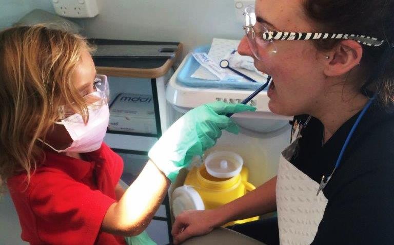 A photo of an audiometry nurse checking child's ears 
