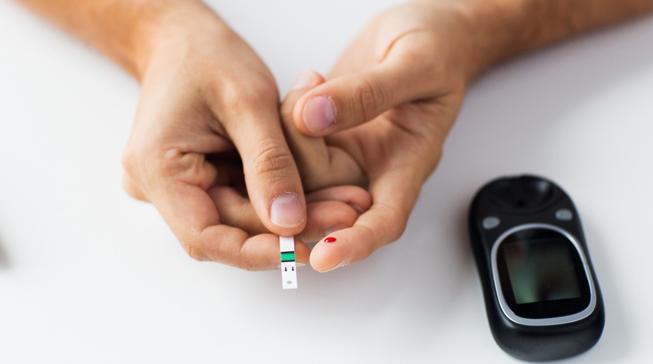 Close up of man checking blood sugar level by glucometer