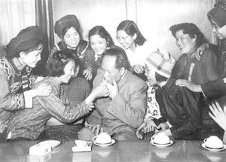 Black and white photo of Mao Zedong with female representatives of the Democracy Youth League of China at the 3rd National Representative Conference in 1957.