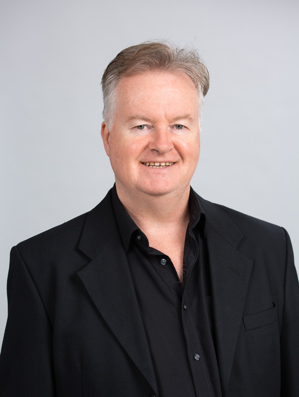 Allan McCay is a middle-aged man wearing a black shirt smiling at the camera