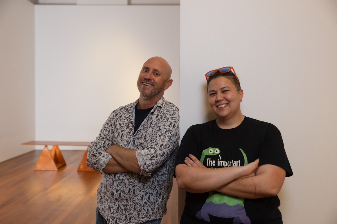 photo of a man and a woman leaning on a white wall